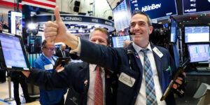 Man on stock trading floor giving thumbs up